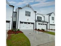 Modern townhome featuring a painted brick exterior, two-car garage, and manicured front yard at 1629 Flint River Se Pl, Smyrna, GA 30126