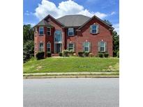 Charming two-story brick home featuring a manicured front yard and a beautiful arched window above the entrance at 1202 Tupelo Chase Ct, Auburn, GA 30011