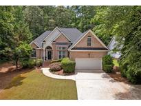 Charming brick home featuring a well-manicured lawn, mature trees, and an attached two-car garage at 8189 N Pine Cone N Dr, Villa Rica, GA 30180