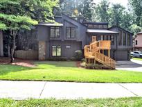 Contemporary home featuring dark siding, a stone accent wall, and a welcoming front porch with natural wood stairs at 2540 Rocky Springs Dr, Marietta, GA 30062