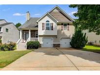 Inviting two-story home with a two-car garage, manicured lawn, and charming stone and siding details at 7125 Creeksong Dr, Douglasville, GA 30134