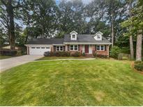Charming brick home with a well-manicured lawn, an attached garage and mature trees at 4023 Oak Crest Dr, Tucker, GA 30084