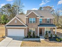 Beautiful two-story brick home with a manicured lawn, covered porch, and a two-car garage at 3505 Aqua Point Pl, Cumming, GA 30041