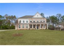 Elegant two-story brick home with a columned front porch and a spacious front yard at 185 Haverling Pass, Hampton, GA 30228