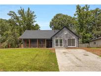 Charming one-story home featuring modern brickwork, a cozy front porch, and a well-manicured lawn at 8689 Cedar Creek Rdg, Riverdale, GA 30274