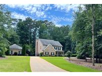 Charming two-story home with a long driveway and lush green lawn, surrounded by mature trees at 115 Green Valley Cir, Mcdonough, GA 30252