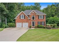 Charming two-story brick home features a well-manicured lawn and an attached two-car garage at 1015 Legacy Walk, Woodstock, GA 30189