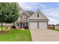 Charming two-story home featuring a stone facade, attached two-car garage, and a beautifully landscaped front yard at 70 Trinity Lane, Covington, GA 30016