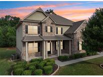Two-story brick home boasts manicured landscaping and a welcoming covered front porch at 6415 Yellow Birch St, Cumming, GA 30040