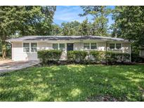Charming single-story home with a well-maintained lawn and mature trees creating a serene curb appeal at 1975 Glenmar Dr, Decatur, GA 30032