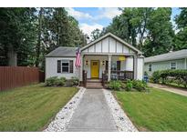 Charming home with a yellow front door and a walkway lined with white stones at 1791 N Olympian Way, Atlanta, GA 30310
