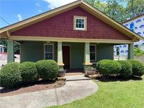 Charming bungalow with a welcoming front porch, lush landscaping, and a colorful exterior paint scheme at 1647 Walker Ave, Atlanta, GA 30337