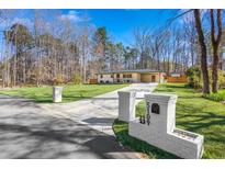 Well-maintained single-story home with a long driveway and brick mailbox on a lush green lawn in a tranquil setting at 5109 Dogwood Hills Dr, Sugar Hill, GA 30518