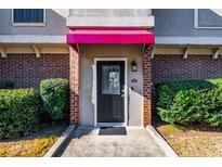 Charming townhome entrance features a black front door with a vibrant pink awning and brick accents at 3301 Henderson Mill Rd # X4, Atlanta, GA 30341