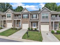Beautifully maintained townhome exterior featuring a well-manicured lawn and attached garages at 7240 Kings Cv # 11, Austell, GA 30168