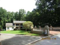 Charming home featuring a well-manicured lawn, mature trees, and a quaint white facade at 5523 Bahia Mar Cir, Stone Mountain, GA 30087