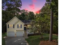 Charming two-story home with a manicured front yard and attached two-car garage and lush landscaping during dusk at 169 Knights Ct, Dallas, GA 30157