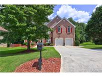 Charming two-story brick home with red shutters, two-car garage, and lush landscaping at 6812 Danforth Way, Stone Mountain, GA 30087