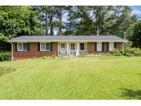 Charming brick ranch-style home with a well-manicured front lawn and a welcoming porch at 999 Chestnut Oak Ct, Lawrenceville, GA 30046