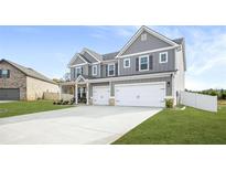 Charming two-story home featuring a gray exterior, manicured lawn and two-car garage at 1049 Bodega Loop, Locust Grove, GA 30248