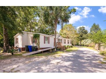 Inviting single-story home with a ramp, complemented by lush landscaping and a spacious driveway at 2991 Blackfish Rd, Johns Island, SC 29455
