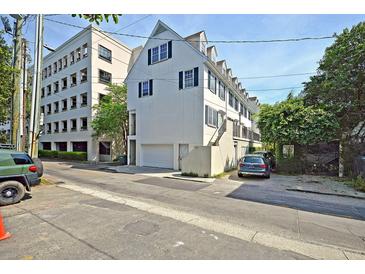 Front view of charming townhome with white exterior, green shutters, and parking at 15 Horlbeck Aly # A-7, Charleston, SC 29401