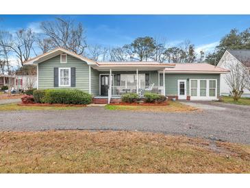 Charming green house with a metal roof, front porch, and landscaped yard at 2007 Central Ave, Summerville, SC 29483