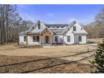 Stunning farmhouse exterior with white siding, wood accents, and a charming front porch at 7210 Raw Dew Dr, Awendaw, SC 29429