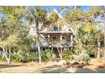 Two-story home with a charming front porch and lush landscaping at 119 Halona Ln, Kiawah Island, SC 29455