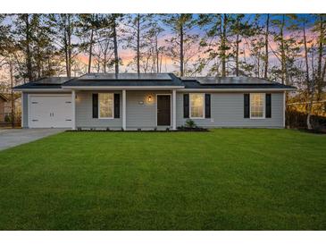 Newly built home with gray siding, solar panels, and a spacious lawn at 444 Longleaf Dr, Summerville, SC 29483