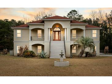Two-story house with stucco siding, red tile roof, and a fountain in the front yard at 4712 Westervelt Rd, Meggett, SC 29449