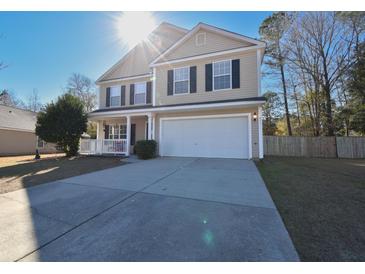 Two-story house with beige siding, white garage door, and a porch at 611 Resinwood Rd, Moncks Corner, SC 29461