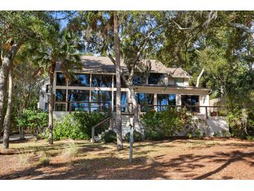 Back of house with large windows and deck, surrounded by lush trees at 2942 Seabrook Island Rd, Seabrook Island, SC 29455