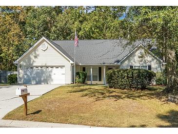 House exterior featuring a two-car garage, manicured lawn, and mature trees at 5382 Westchester Pl, North Charleston, SC 29418