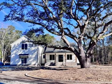 Two-story white farmhouse with a large oak tree and brick walkway at 3874 Srevir Rd, Johns Island, SC 29455