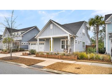 Gray house with yellow door, two-car garage, and landscaped yard at 327 Great Lawn Dr, Summerville, SC 29486