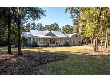 Gray farmhouse with metal roof, large porch, and landscaped yard at 3365 Westphal Dr, Johns Island, SC 29455