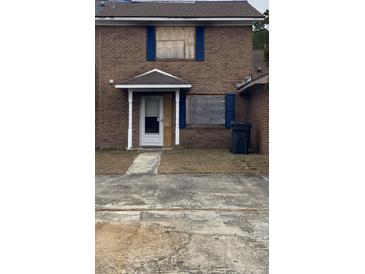 Brick townhouse with boarded windows and a small front yard at 7734 Suzanne Dr, North Charleston, SC 29418