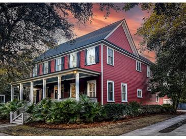 Two-story red house with a wrap-around porch, white columns, and lush landscaping at 283 Beresford Creek St, Charleston, SC 29492