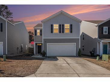Two-story house with gray siding, white garage door, and landscaping at 9702 Roseberry St, Ladson, SC 29456