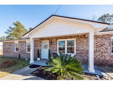 Brick ranch house with a light blue front door and landscaping at 9772 Berrywood Dr, Ladson, SC 29456