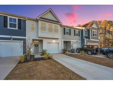 Two-story townhome with gray and white siding, two-car garage, and landscaping at 553 Trotters Ln, Moncks Corner, SC 29461