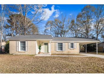 Brick ranch house with carport, landscaping, and a green door at 7640 Hillview Ln, North Charleston, SC 29420