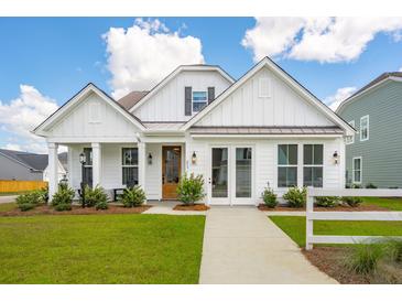White farmhouse exterior with a brown door, landscaping, and walkway at 780 Opal Wing St, Moncks Corner, SC 29461