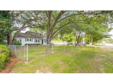 White house with grey roof, surrounded by trees and a chain link fence at 1225 Central Ave, Summerville, SC 29483