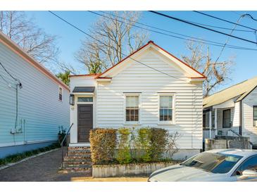 Charming white cottage with a red roof, brick steps, and a well-manicured front yard at 17 H St, Charleston, SC 29403