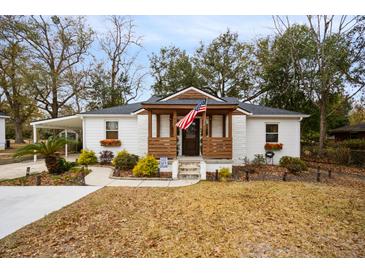 Charming white house with brown accents, a porch, and a well-maintained lawn at 1024 Holcombe Rd, Hanahan, SC 29410