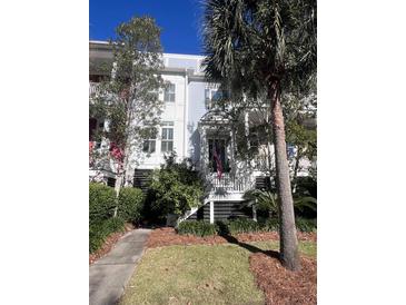 Three-story townhome with white siding, landscaping, and a flag at 2024 Amenity Park Dr, Mount Pleasant, SC 29466