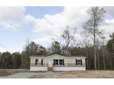 Tan and beige single-wide manufactured home with black windows, wooden steps, and surrounding woodland at 520 Branch Bend Way, Cross, SC 29436