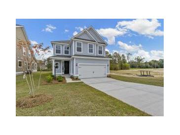 Two-story home with gray siding, attached garage, and landscaped lawn at 323 Abercom Place Dr, Moncks Corner, SC 29461